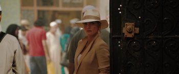 Movie still from “The 355” (2022), directed by Simon Kinberg – A woman wearing a white hat standing in front of a door; Close Up shot, Over the shoulder angle