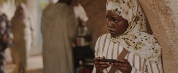 Movie still from “The 355” (2022), directed by Simon Kinberg – A young woman looking at a cell phone; Close Up shot, Over the shoulder angle