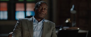 Movie still from “The 355” (2022), directed by Simon Kinberg – An older man in a suit and tie looking at the camera; Close Up shot, Over the shoulder angle
