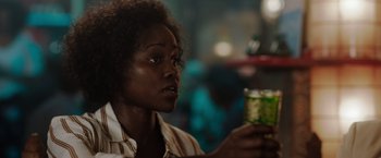 Movie still from “The 355” (2022), directed by Simon Kinberg – A woman holding a glass in her hand; Close Up shot, Over the shoulder angle