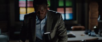 Movie still from “The 355” (2022), directed by Simon Kinberg – A man in a gray suit is looking down; Close Up shot, High angle