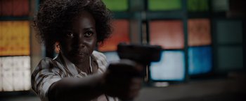 Movie still from “The 355” (2022), directed by Simon Kinberg – A woman is holding a gun in her hand; Close Up shot, Over the shoulder angle