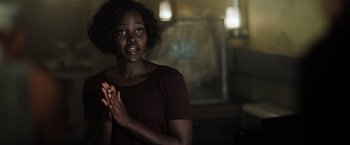 Movie still from “The 355” (2022), directed by Simon Kinberg – A woman claps her hands while standing in a dark room; Close Up shot, Over the shoulder angle