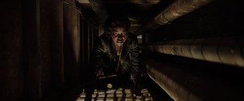 Movie still from “The 355” (2022), directed by Simon Kinberg – A person in a dark room holding a bat; Medium shot, Low angle