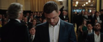 Movie still from “The 355” (2022), directed by Simon Kinberg – A person wearing a suit and tie; Close Up shot, Low angle