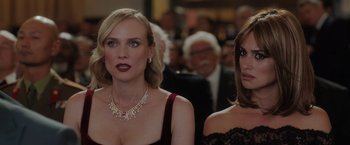 Movie still from “The 355” (2022), directed by Simon Kinberg – Two women are standing next to each other in front of a group of people; Close Up shot, Over the shoulder angle
