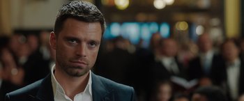 Movie still from “The 355” (2022), directed by Simon Kinberg – A person wearing a suit and tie; Close Up shot, Over the shoulder angle
