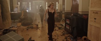 Movie still from “The 355” (2022), directed by Simon Kinberg – A woman in a black dress walking down a hall way; Wide shot, High angle