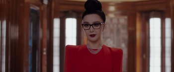Movie still from “The 355” (2022), directed by Simon Kinberg – A woman in a red dress wearing glasses and a necklace; Close Up shot, Low angle