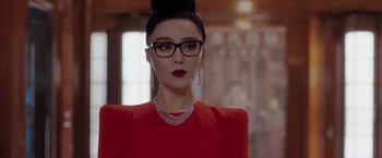 Movie still from “The 355” (2022), directed by Simon Kinberg – A woman in a red dress wearing glasses and a necklace; Close Up shot, Over the shoulder angle