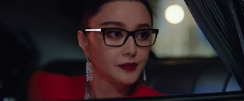 Movie still from “The 355” (2022), directed by Simon Kinberg – A person wearing glasses and a red shirt; Close Up shot, Over the shoulder angle