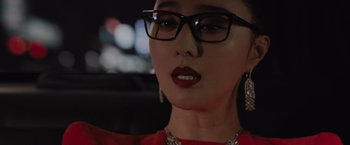 Movie still from “The 355” (2022), directed by Simon Kinberg – A person wearing glasses in a car; Close Up shot, Over the shoulder angle