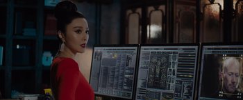 Movie still from “The 355” (2022), directed by Simon Kinberg – A woman standing in front of two computer monitors; Close Up shot, Over the shoulder angle