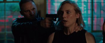 Movie still from “The 355” (2022), directed by Simon Kinberg – A man and a woman holding a gun in a room; Close Up shot, Over the shoulder angle