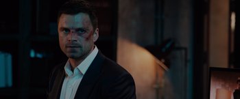 Movie still from “The 355” (2022), directed by Simon Kinberg – A person wearing a suit; Close Up shot, Over the shoulder angle