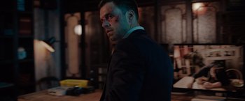 Movie still from “The 355” (2022), directed by Simon Kinberg – A person wearing a suit; Close Up shot, Over the shoulder angle