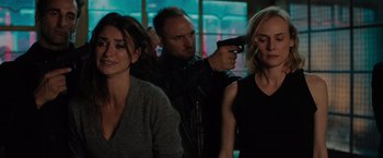 Movie still from “The 355” (2022), directed by Simon Kinberg – A man pointing a gun at two women in front of a window; Medium shot, Over the shoulder angle