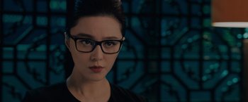 Movie still from “The 355” (2022), directed by Simon Kinberg – A woman wearing glasses and a black shirt; Close Up shot, Over the shoulder angle