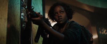 Movie still from “The 355” (2022), directed by Simon Kinberg – A woman holding a gun in a dark room; Close Up shot, Over the shoulder angle