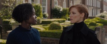 Movie still from “The 355” (2022), directed by Simon Kinberg – Two women standing next to each other in front of bushes; Close Up shot, Over the shoulder angle