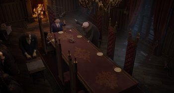 Movie still from “The Addams Family 2” (2021), directed by Greg Tiernan – Two people sitting at a long table in a room; Wide shot, High angle