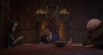 Movie still from “The Addams Family 2” (2021), directed by Greg Tiernan – A man sitting at a dinner table in front of a fireplace; Wide shot, High angle