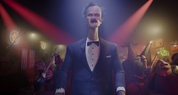 Movie still from “The Addams Family 2” (2021), directed by Greg Tiernan – A man in a suit and tie smoking a cigarette; Medium shot, Low angle