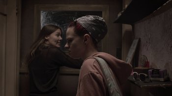 Movie still from “The Amityville Moon” (2021), directed by Thomas J. Churchill – A woman is brushing the hair of another woman in front of a mirror; Medium shot, Over the shoulder angle