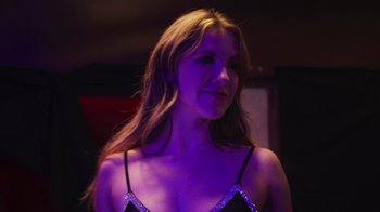 Movie still from “The Amityville Moon” (2021), directed by Thomas J. Churchill – A beautiful woman in a black top in a purple room; Close Up shot, Low angle