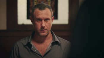 Movie still from “The Amityville Moon” (2021), directed by Thomas J. Churchill – A person wearing a gray shirt; Close Up shot, Over the shoulder angle