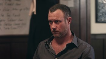 Movie still from “The Amityville Moon” (2021), directed by Thomas J. Churchill – A person wearing a gray shirt; Close Up shot, Over the shoulder angle