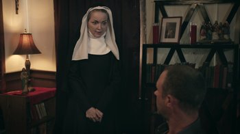 Movie still from “The Amityville Moon” (2021), directed by Thomas J. Churchill – A woman wearing a nun's habit and a white head scarf; Medium shot, Over the shoulder angle