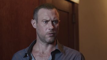 Movie still from “The Amityville Moon” (2021), directed by Thomas J. Churchill – A person wearing a gray shirt; Close Up shot, Low angle