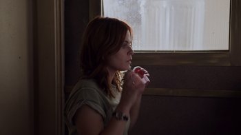 Movie still from “The Amityville Moon” (2021), directed by Thomas J. Churchill – A woman holding a nintendo wii game controller in front of a window; Close Up shot, Low angle