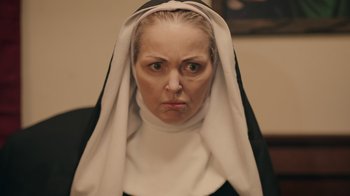 Movie still from “The Amityville Moon” (2021), directed by Thomas J. Churchill – A woman wearing a nun's habit with a frowning look on her face; Close Up shot, Low angle