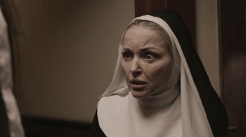 Movie still from “The Amityville Moon” (2021), directed by Thomas J. Churchill – A woman wearing a nun's habit looking at the camera; Close Up shot, Low angle