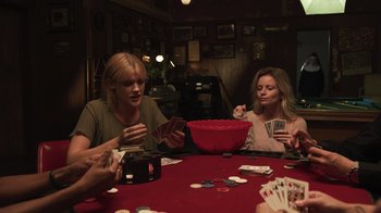 Movie still from “The Amityville Moon” (2021), directed by Thomas J. Churchill – A group of women sitting at a table playing cards; Medium shot, High angle