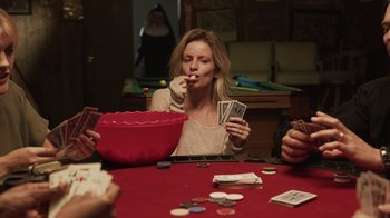 Movie still from “The Amityville Moon” (2021), directed by Thomas J. Churchill – A woman sitting at a table with cards in her hands; Medium shot, Over the shoulder angle