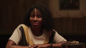 Movie still from “The Amityville Moon” (2021), directed by Thomas J. Churchill – A woman sitting at a table with her hand on her chin; Close Up shot, Over the shoulder angle