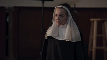 Movie still from “The Amityville Moon” (2021), directed by Thomas J. Churchill – A woman dressed as a nun in a black and white outfit; Close Up shot, Over the shoulder angle