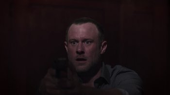 Movie still from “The Amityville Moon” (2021), directed by Thomas J. Churchill – A man holding a cell phone in a dark room; Close Up shot, Low angle