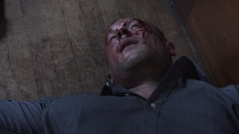 Movie still from “The Amityville Moon” (2021), directed by Thomas J. Churchill – A man laying on the ground with a knife in his face; Close Up shot, Overhead angle