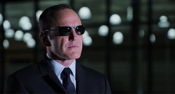Movie still from “The Avengers” (2012), directed by Joss Whedon – A man in a black suit and sunglasses looking to his left; Close Up shot, Low angle