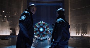 Movie still from “The Avengers” (2012), directed by Joss Whedon – Two men standing in front of an iron man arc reactor; Medium shot, Over the shoulder angle