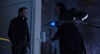 Movie still from “The Avengers” (2012), directed by Joss Whedon – Two men in a room one is holding a sword and the other is holding something blue; Medium shot, Over the shoulder angle
