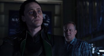 Movie still from “The Avengers” (2012), directed by Joss Whedon – A man standing next to another man in a dark room; Close Up shot, Over the shoulder angle