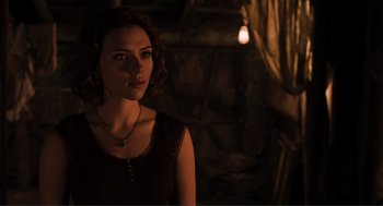 A woman in a dark room with a light hanging from the ceiling