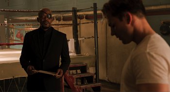 Movie still from “The Avengers” (2012), directed by Joss Whedon – A man in a black suit is looking at another man in a black suit; Medium shot, Over the shoulder angle