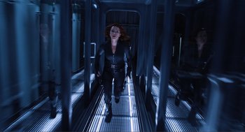 Movie still from “The Avengers” (2012), directed by Joss Whedon – A woman in a black outfit walking down a metal walkway; Wide shot, Low angle