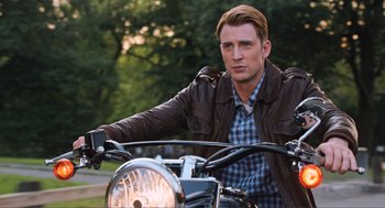 Movie still from “The Avengers” (2012), directed by Joss Whedon – A man sitting on the back of a motorcycle wearing a leather jacket; Medium shot, Low angle